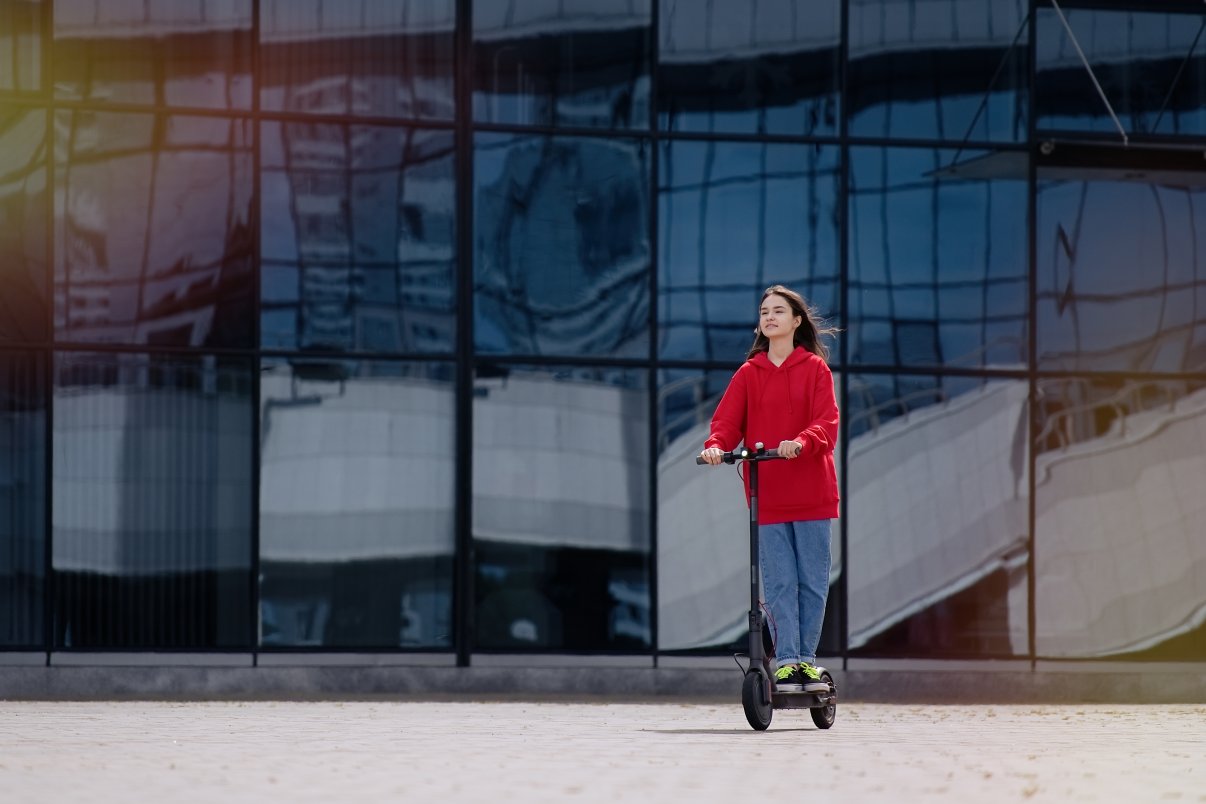 young teenager girl on a kick scooter in urban landscape