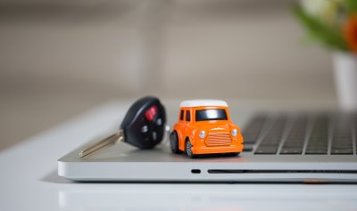 Miniature car and car keys on laptop keyboard