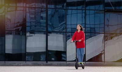young teenager girl on a kick scooter in urban landscape