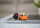 Miniature car and car keys on laptop keyboard